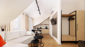 A modern apartment with a loft-style living area, a kitchenette, and a wooden wardrobe. - Hetman Main Square Apartments (Kraków)