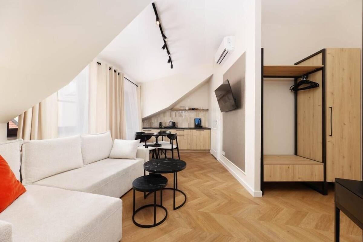 A modern apartment with a loft-style living area, a kitchenette, and a wooden wardrobe.