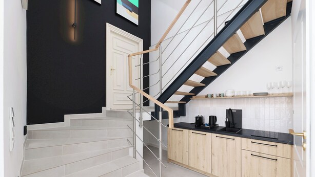 A modern kitchen with a wooden staircase and a black wall. - Hetman Main Square Apartments (Kraków)