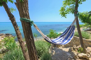 Una hamaca atada entre dos árboles con vistas a una playa y agua azul cristalina.