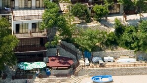 Un hotel frente a la playa con varias construcciones, una playa de arena y sombrillas.