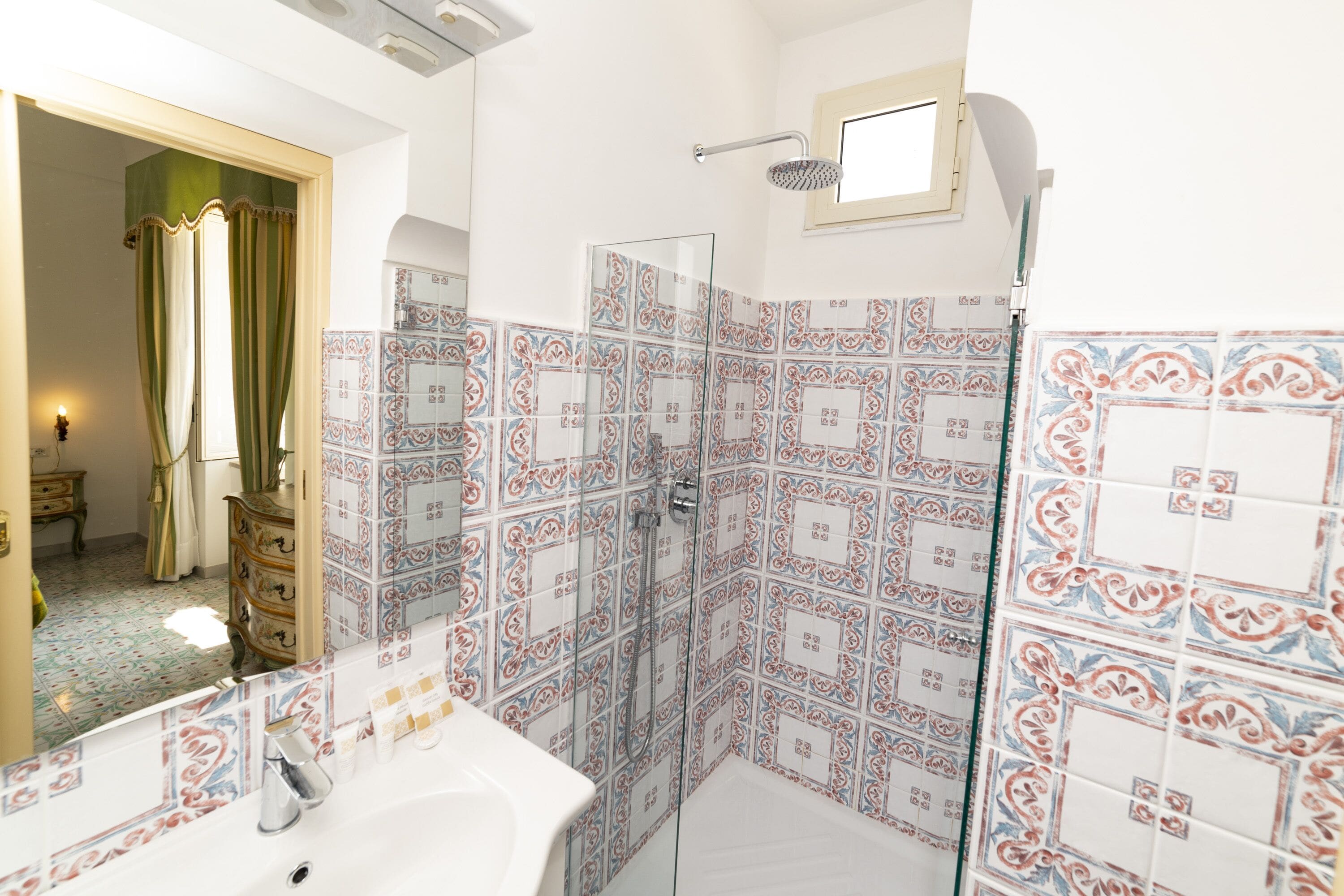 Un baño con baldosas estampadas, una ducha y un lavamanos.