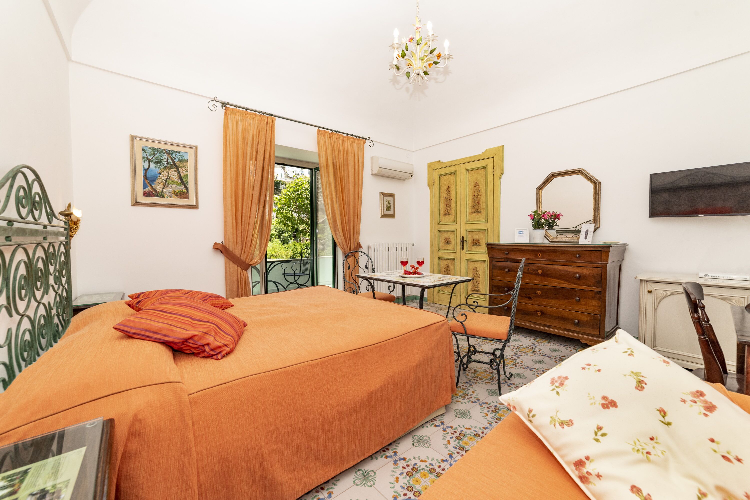 A bedroom with a bed, a table, a chair, a dresser, and a window with curtains.