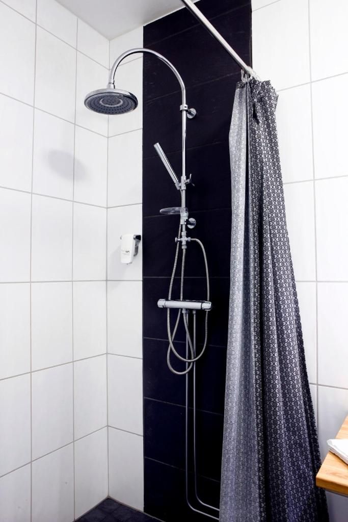 A shower with a handheld showerhead, a wall-mounted faucet, and a shower caddy.
