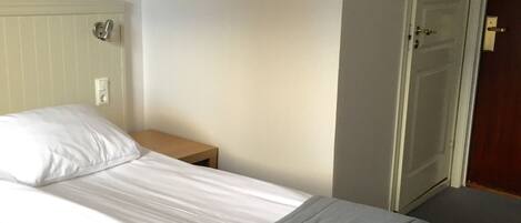 Un dormitorio con una cama, una mesita de noche, un cuadro enmarcado en la pared y una puerta.