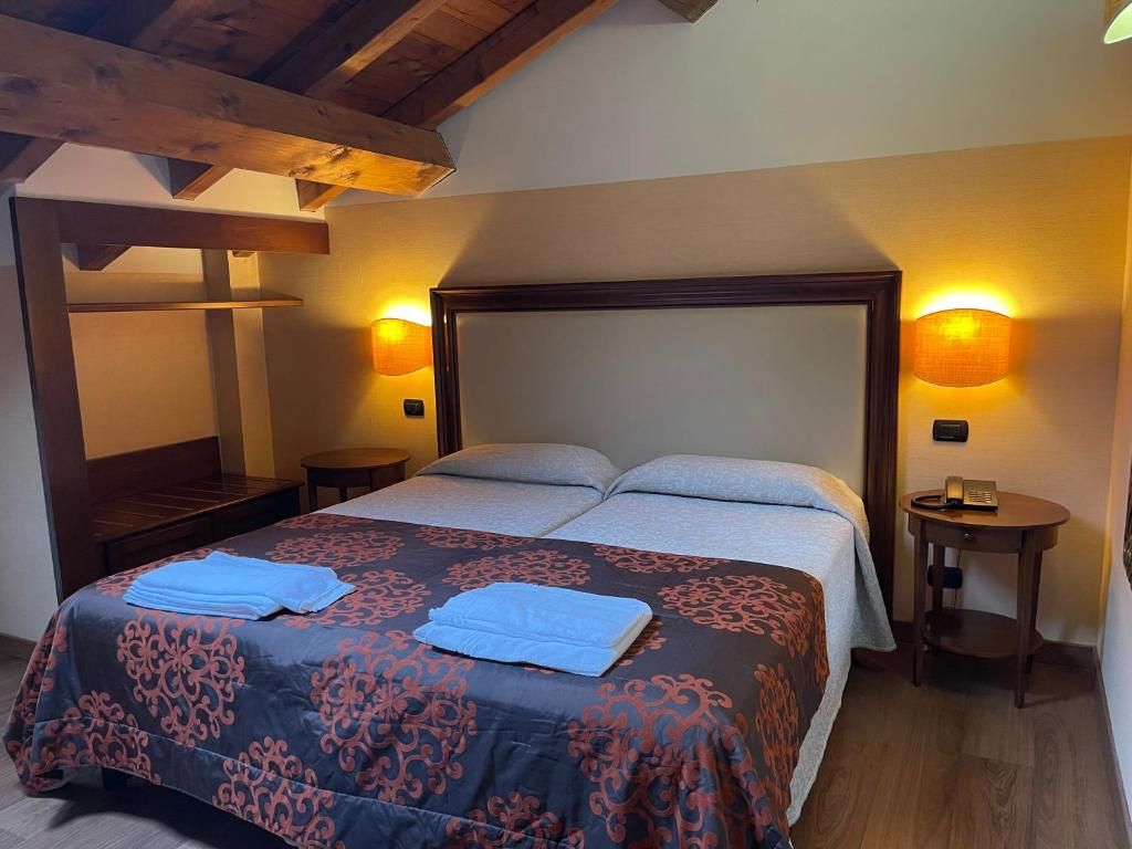 Ein Schlafzimmer mit einem großen Bett, zwei Nachttischen und einer Holzbalkendecke.