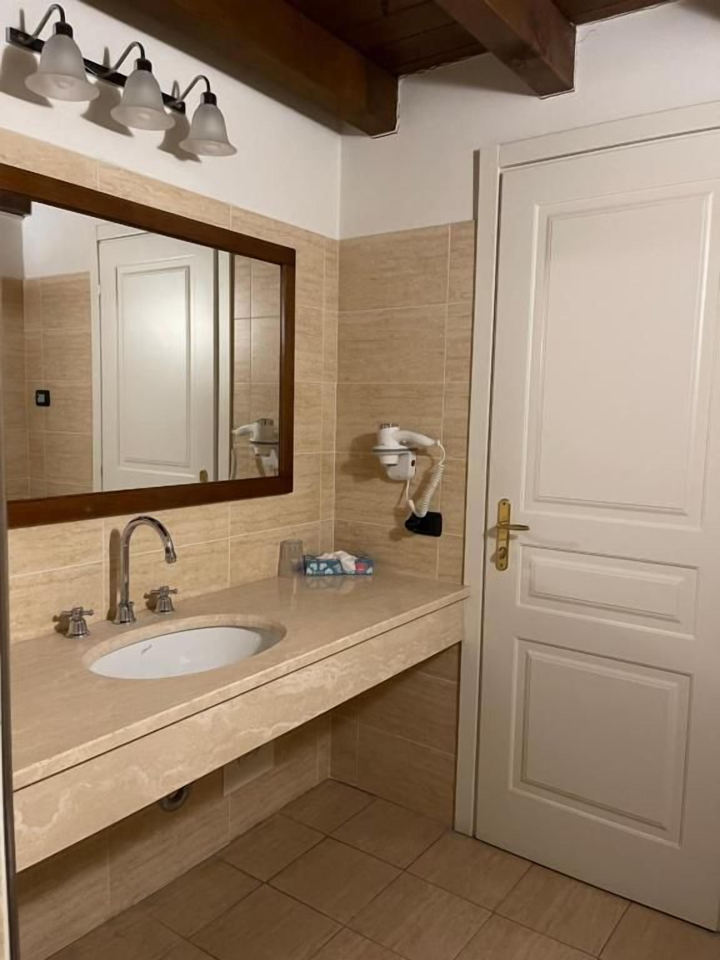 Un baño con lavamanos, espejo y toallero.