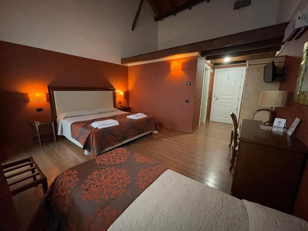 Une chambre d’hôtel avec deux lits, un bureau, une chaise et une porte.