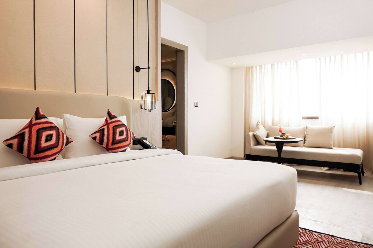 Une chambre d ’hôtel avec un grand lit, un canapé, une petite table et un dressing.