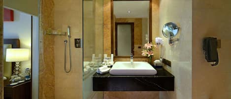 Un baño moderno con ducha envuelta en vidrio, tocador con lavabo y espejo.