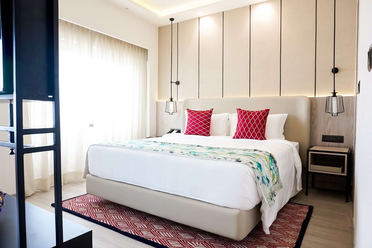 Una habitación de hotel moderna con una cama grande, una mesita de noche y otra mesilla.