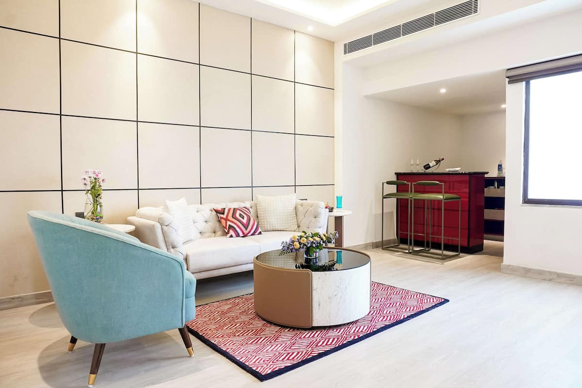 Un salon moderne avec un canapé, une table basse ronde et un tapis aux motifs rouges et blancs.