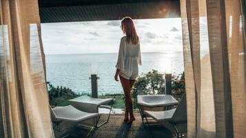 Una mujer de pie en un umbral con vista a una piscina y al océano.