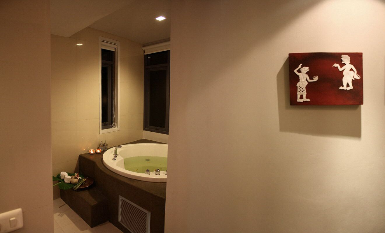A bathroom with a large bathtub, a window, and a wall-mounted artwork.