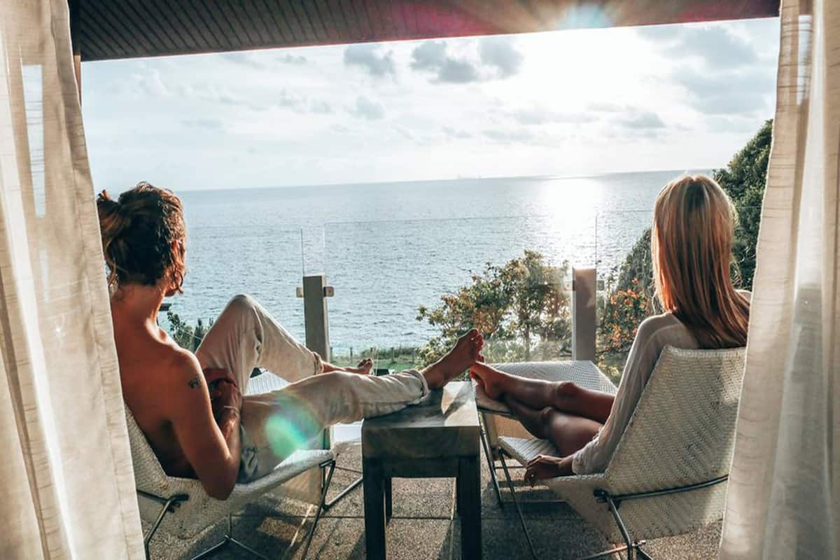 Two people relaxing on a balcony with a view of the sea.