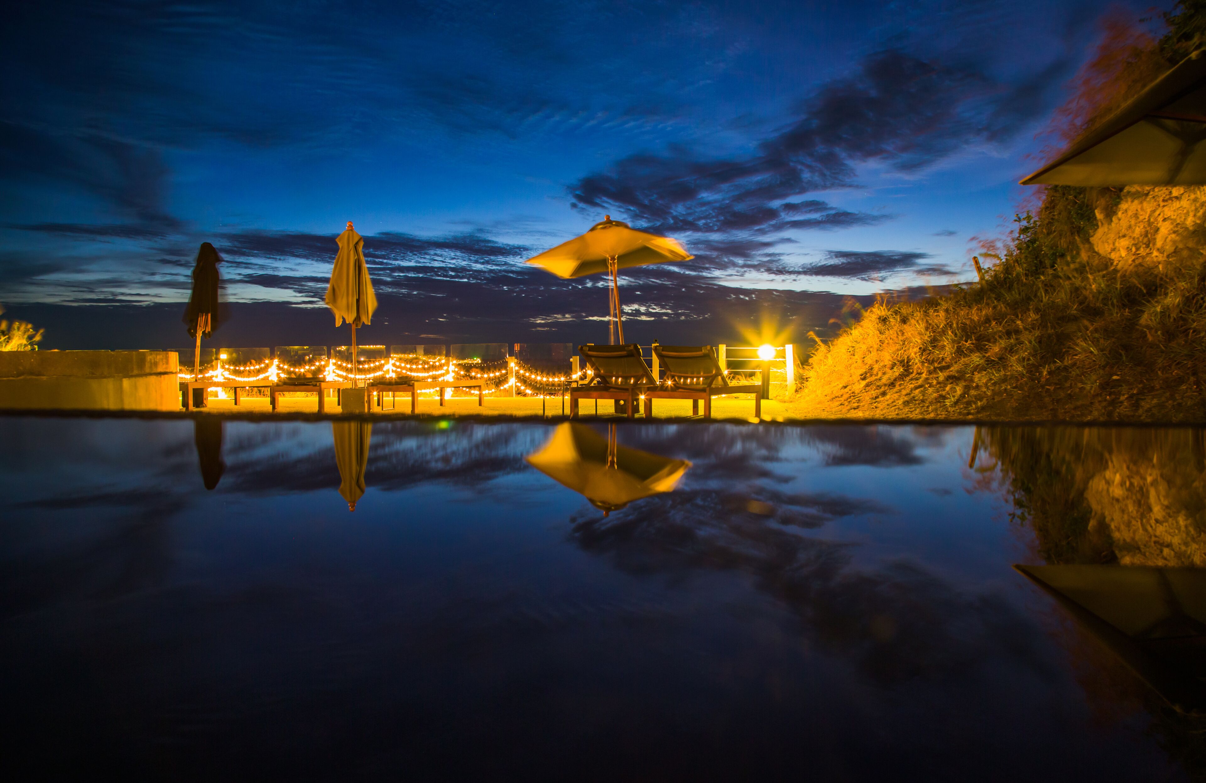 Una piscina al aire libre, sombrillas, sillones reclinables de piscina