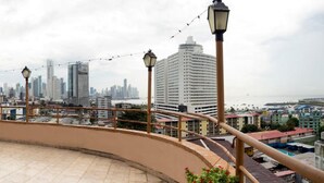 A balcony with a city view, featuring a curved railing and a palm tree. - Hotel República (Panama City)