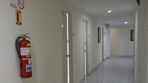 A corridor with tiled flooring, doors, and a fire extinguisher mounted on the wall. - Hotel República (Panama City)