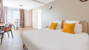 Habitación de hotel con una cama grande, dos almohadas, un escritorio con silla y una ventana con cortinas.