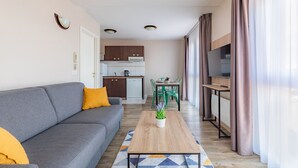 Una sala moderna con un sofá gris, una mesa de centro de madera y un comedor con sillas verdes.