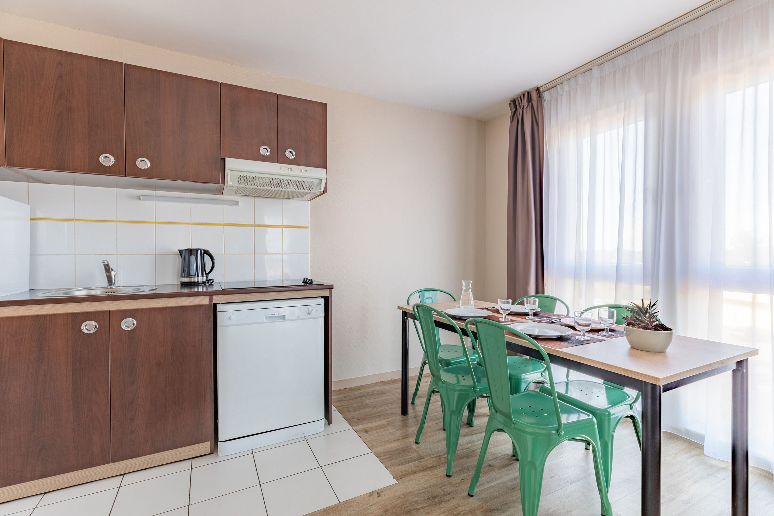 Une cuisine moderne avec des meubles en bois, un lave-vaisselle et un coin repas comprenant une table et des chaises.