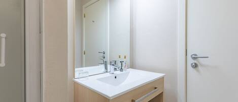 Une salle de bain moderne avec un lavabo blanc, un meuble-lavabo en bois et un miroir.