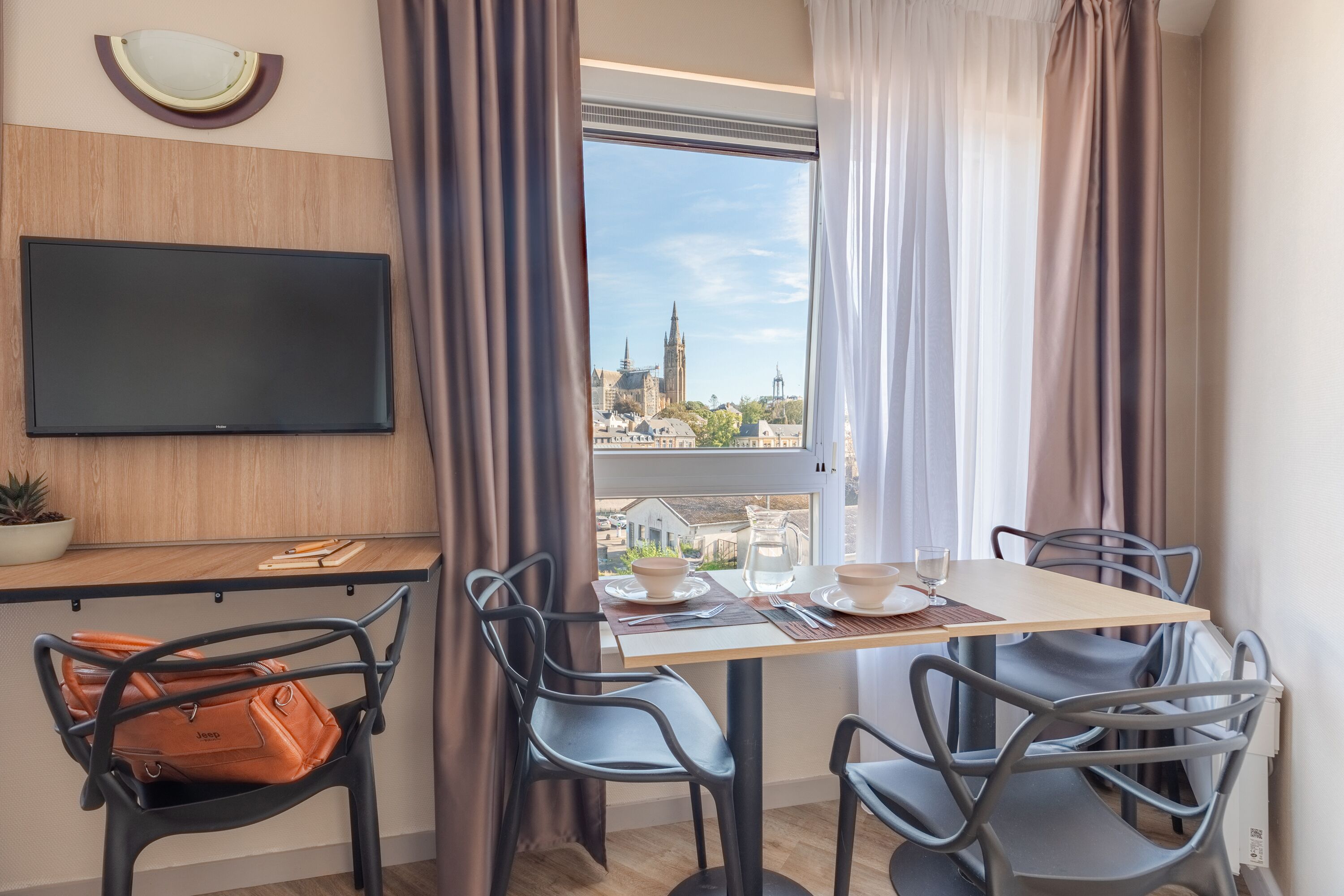 Una habitación moderna con una mesa de comedor, sillas, televisión y vistas a un paisaje urbano.