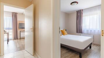 A hotel room with a bed, a desk, and a television.