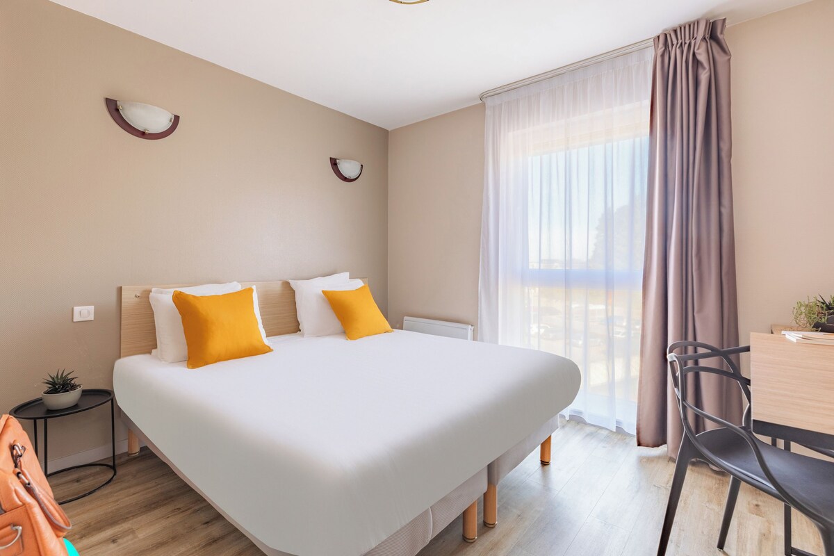 Une chambre d’hôtel avec un grand lit, un bureau et une chaise.