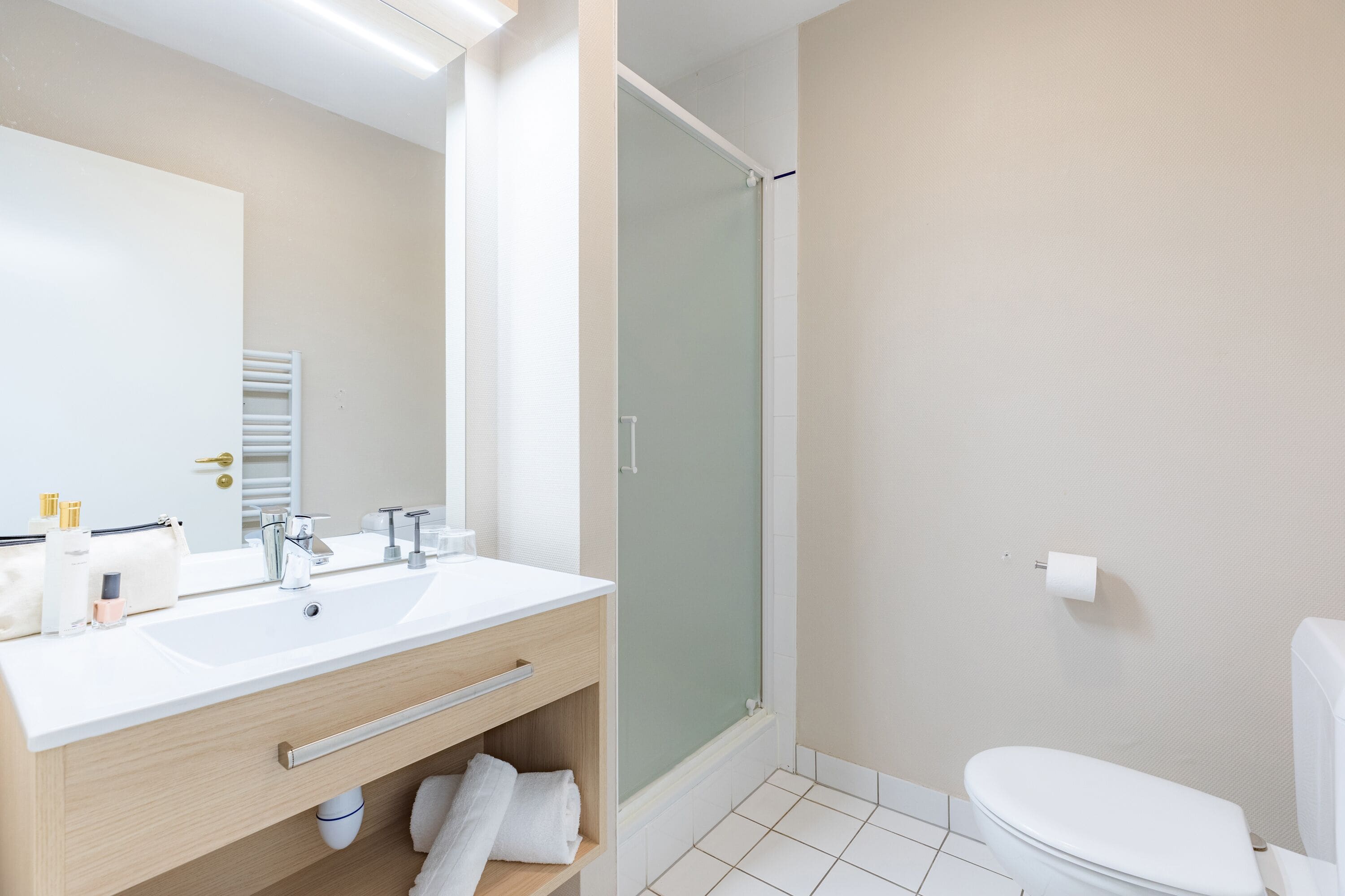 A modern bathroom with a double sink vanity, a glass shower enclosure, and a toilet.
