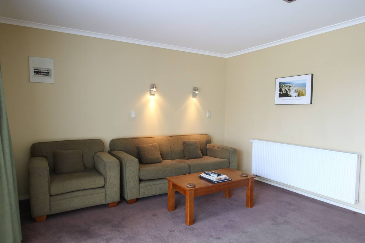 A living room with a green sofa, a wooden coffee table, and two wall-mounted lights.