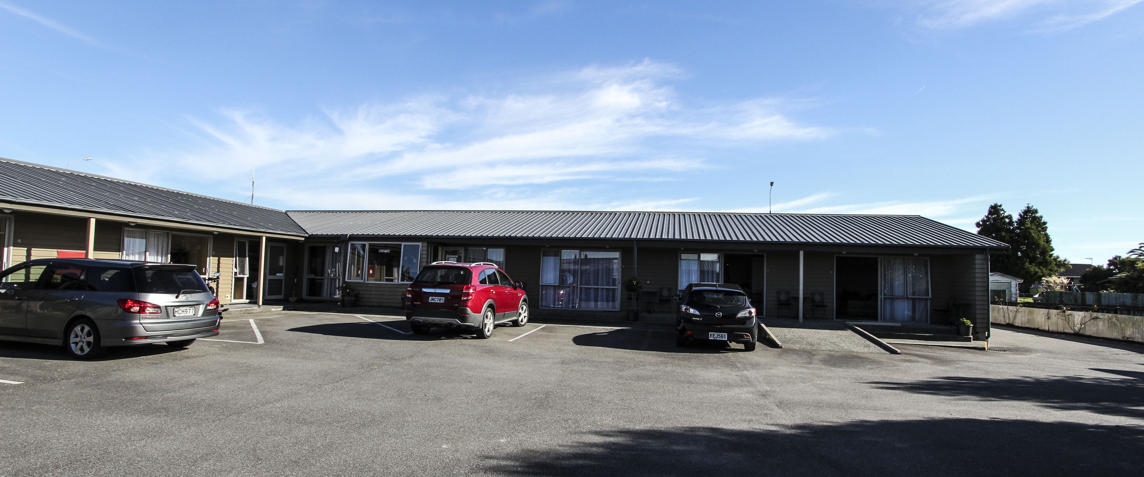 A building with a parking lot containing three cars.