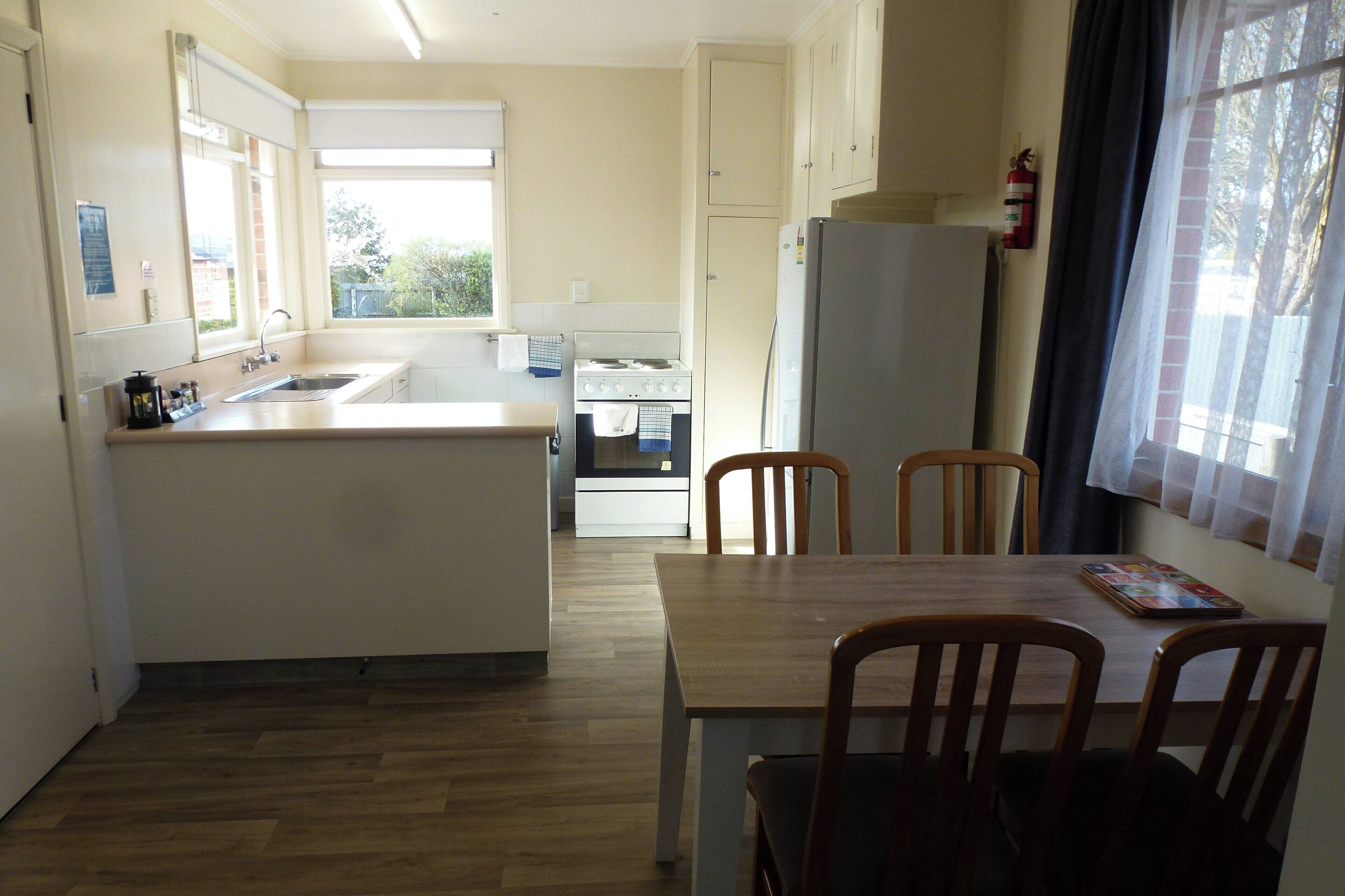 Une cuisine compacte dotée d’un îlot central, d’une table à manger avec des chaises et d’un réfrigérateur.