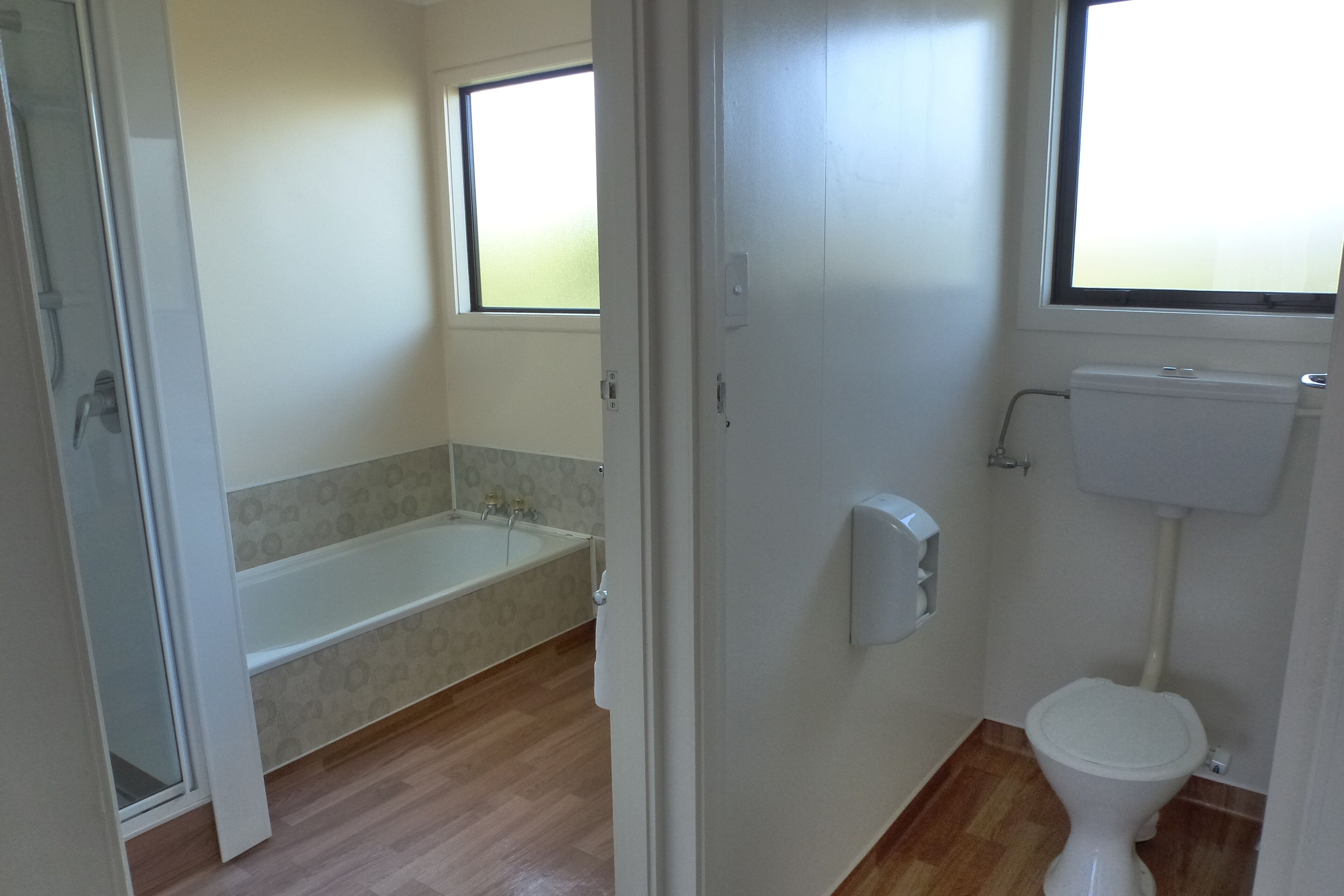 A bathroom with a toilet, a bathtub, and a window.