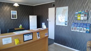 A reception desk with a framed certificate, a clock, and a map. - ASURE Adcroft Motel (Ashburton)