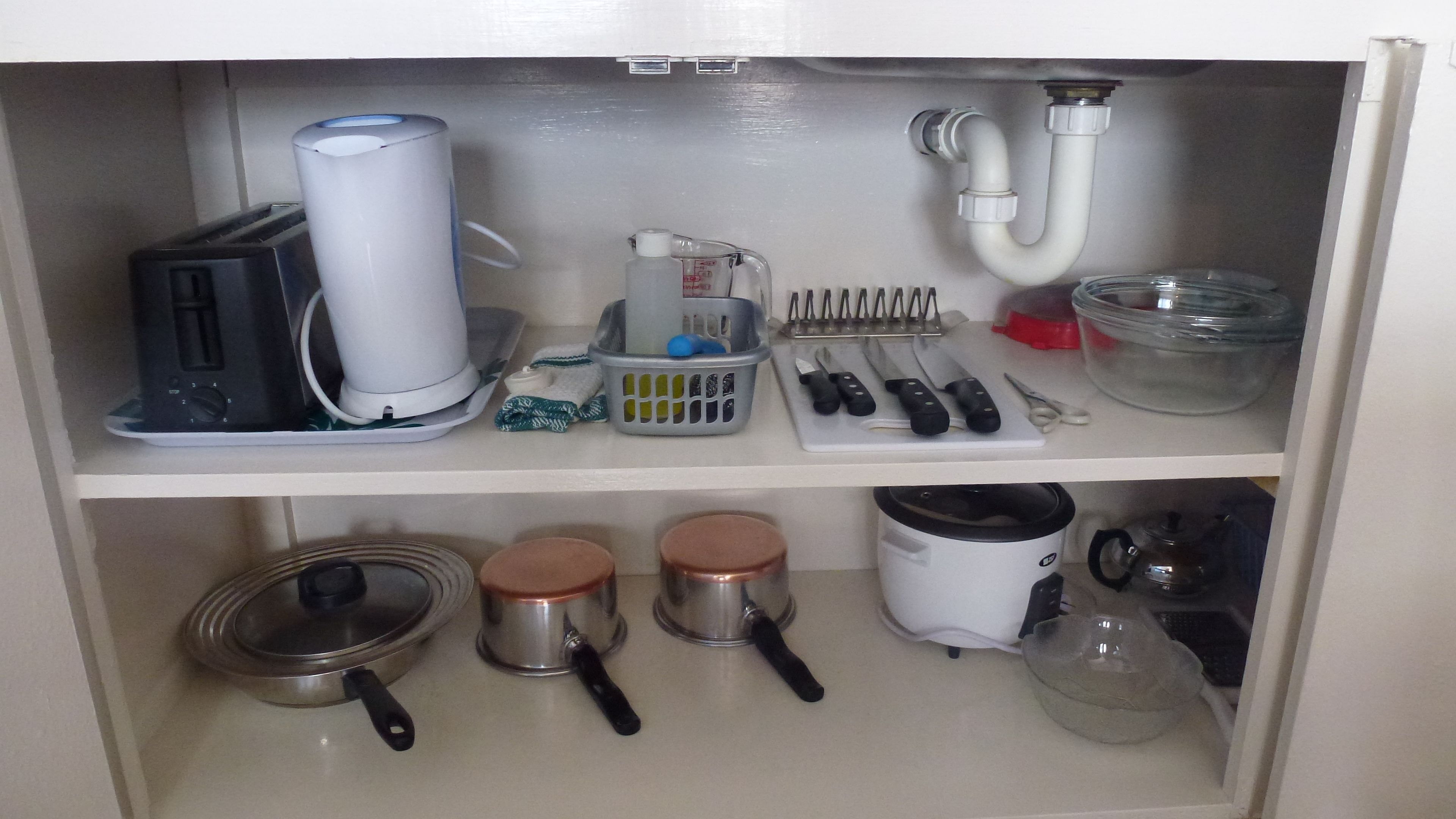 A kitchen with a coffee maker, kettle, and various utensils on the countertop.