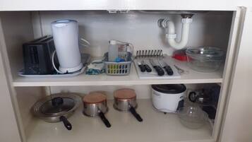A kitchen with a coffee maker, kettle, and various utensils on the countertop.