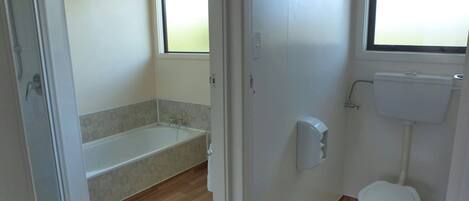 Une salle de bain avec des toilettes, une baignoire et une fenêtre.