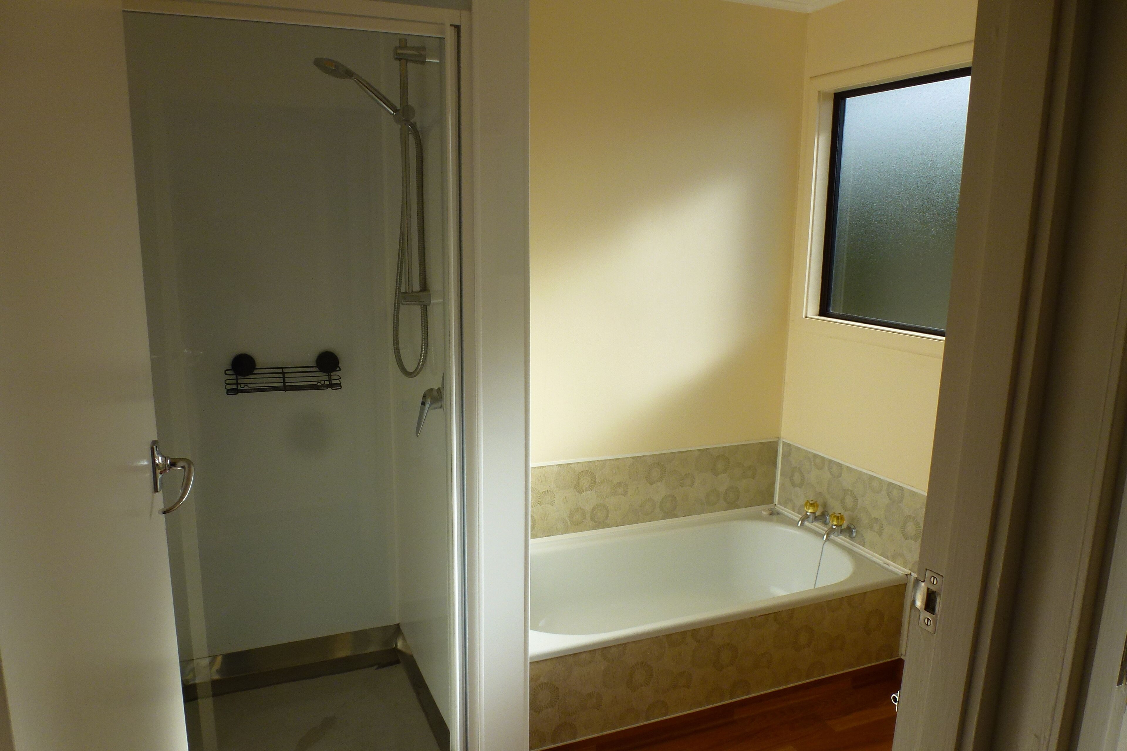 A bathroom with a shower, a bathtub, and a window.