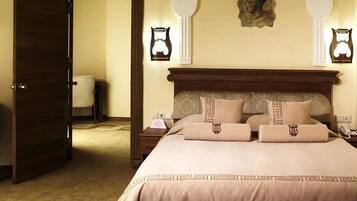 A hotel room with a large bed, bedside tables, a chair, and wall-mounted lamps.