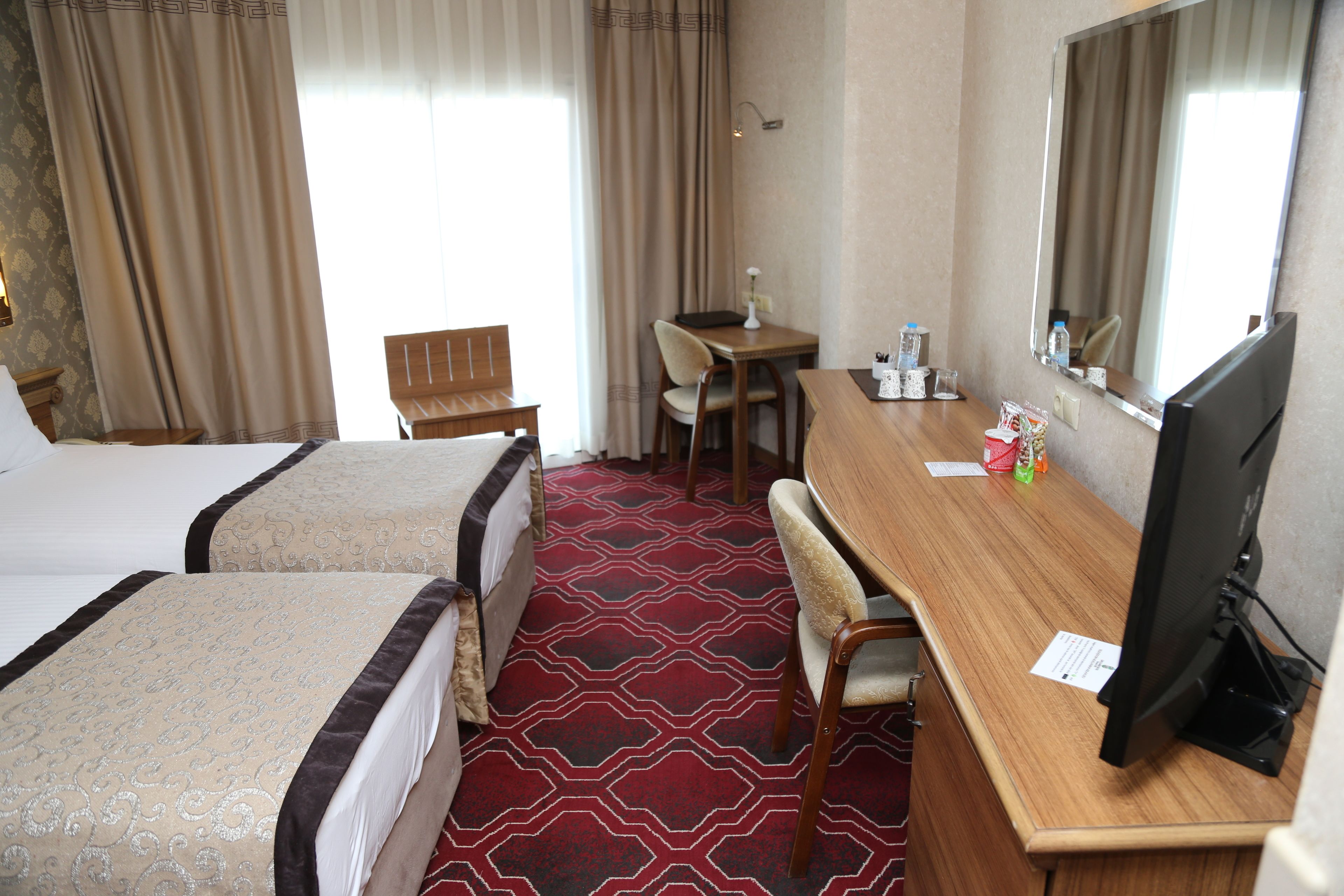 Habitación de hotel con dos camas, un escritorio, una computadora, una silla y una mesita.