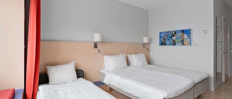 Habitación de hotel con dos camas, cortina roja, cabecero de madera, un cuadro en la pared y suelo de madera.