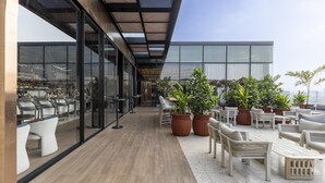 Terraço no telhado com área de estar ao ar livre, plantas em vasos e vista para o horizonte da cidade.