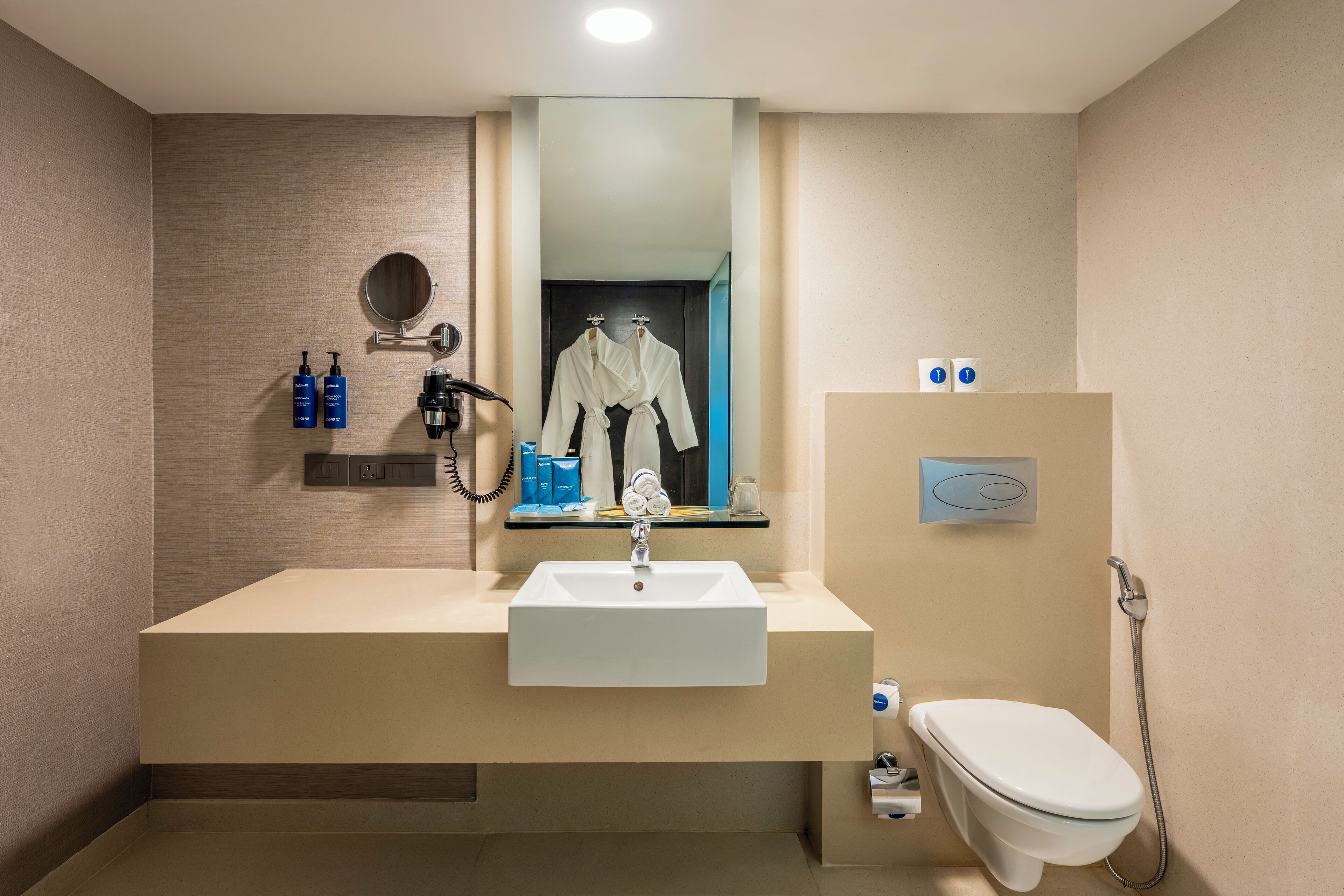 A modern bathroom with a large sink, mirror, and toilet.