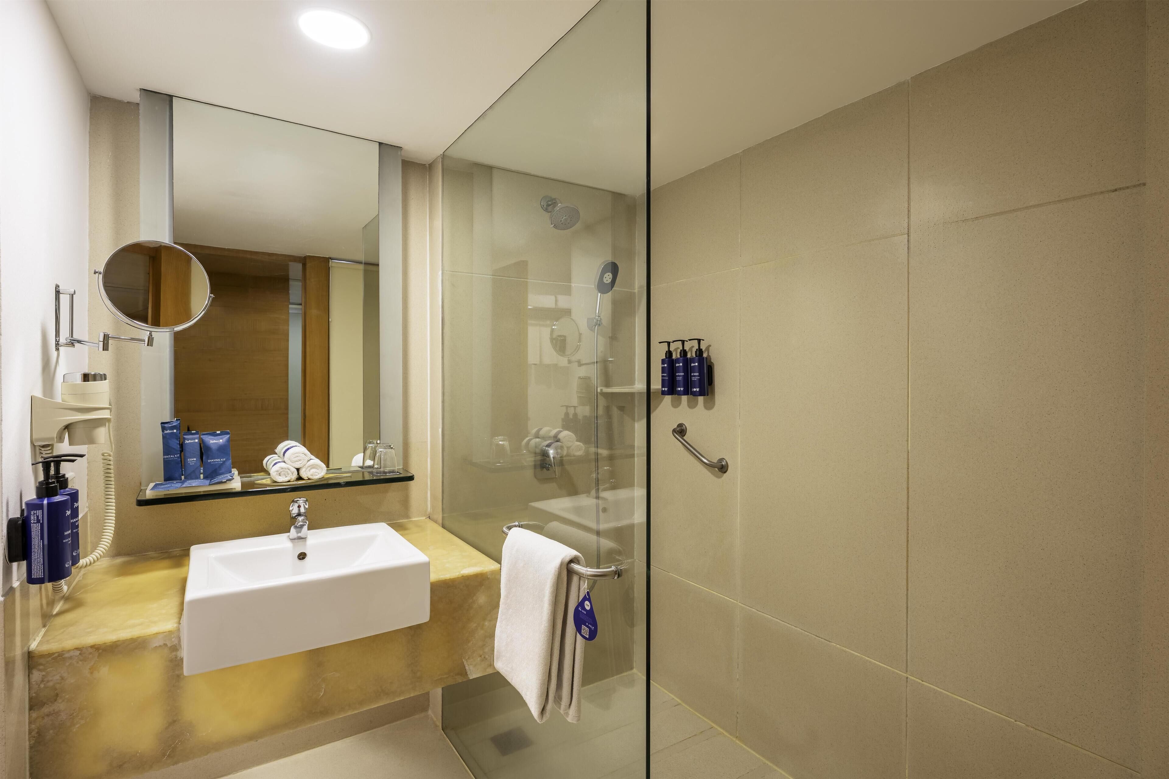 Une salle de bain moderne avec une douche à parois de verre, un lavabo blanc et un miroir.