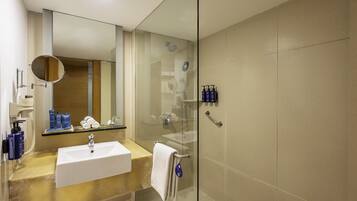 Une salle de bain moderne avec une douche à parois de verre, un lavabo blanc et un miroir.