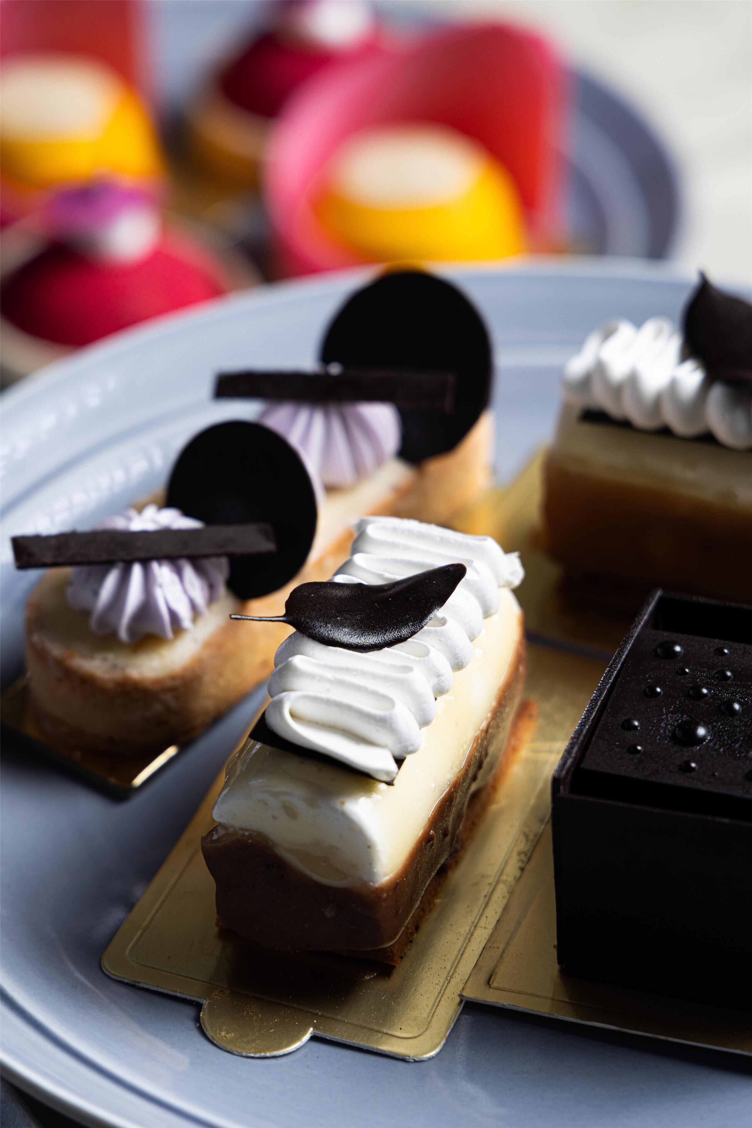 A variety of desserts on a plate, including a chocolate tart with a chocolate leaf garnish.