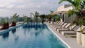 Piscina no terraço com espreguiçadeiras e plantas em vasos.