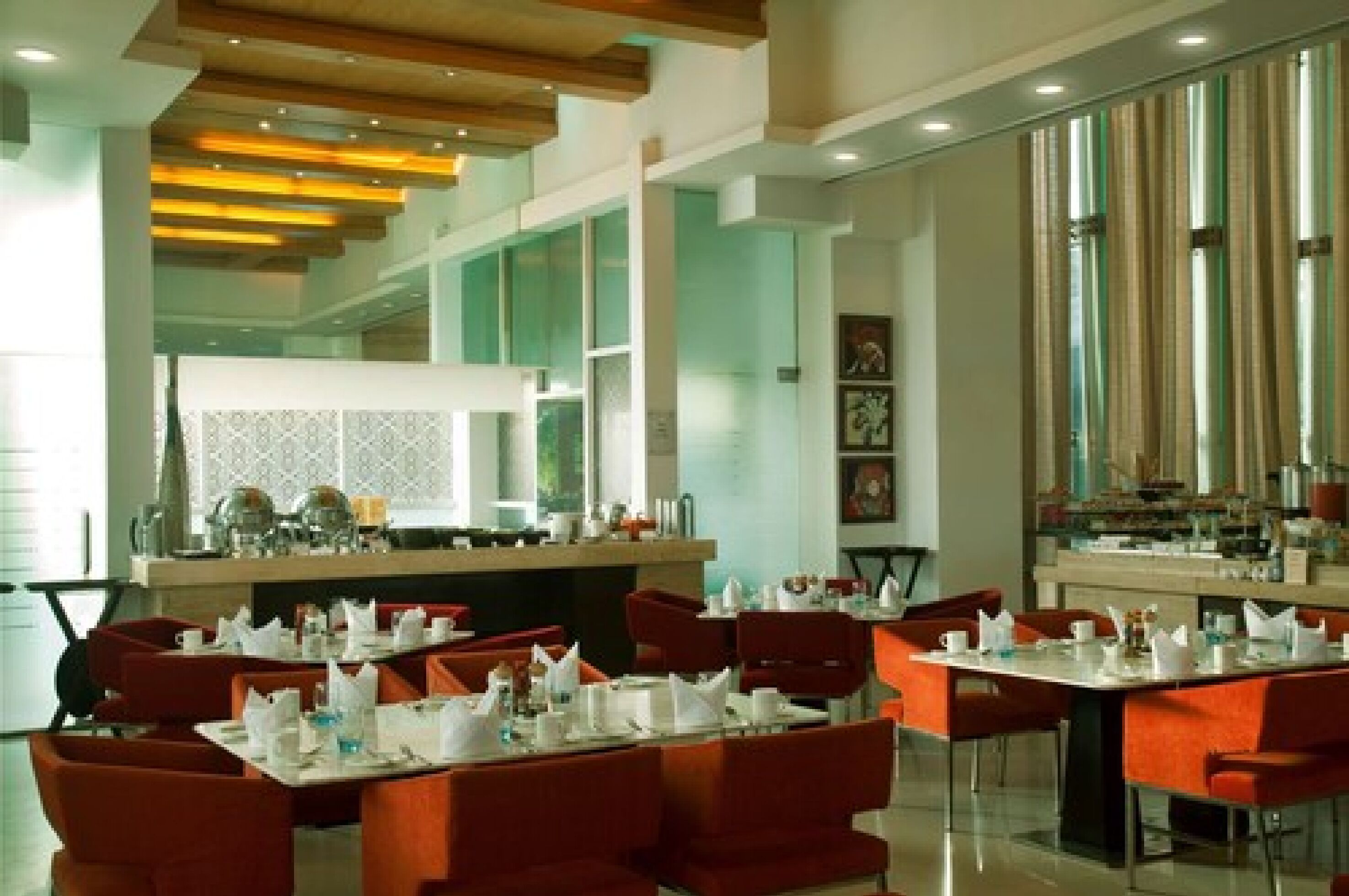 Ein modernes Restaurant mit roten Stühlen und Tischen, einer Theke mit Speisekarte und großen Fenstern.