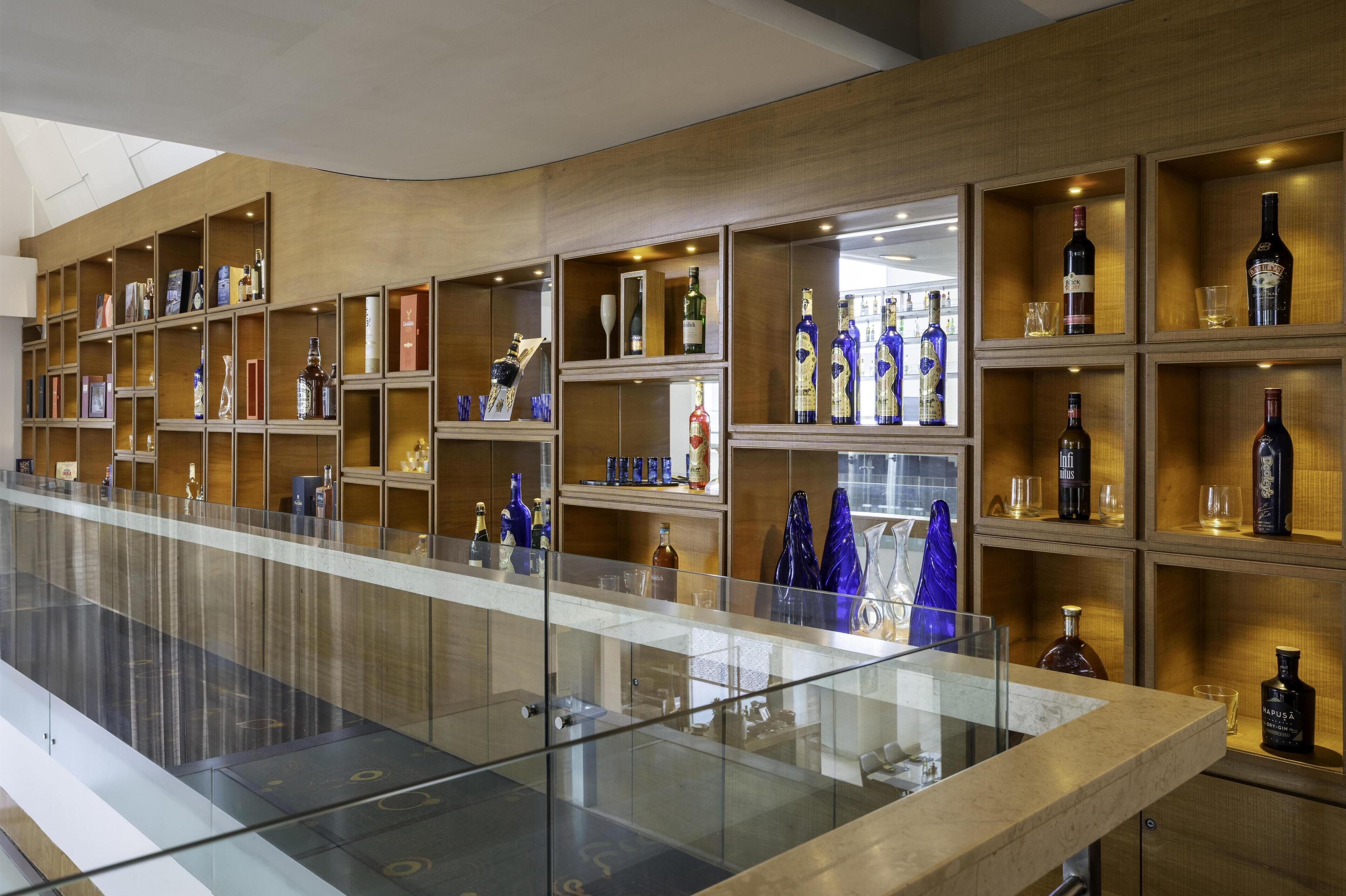 A modern bar with shelves of liquor bottles and glasses.